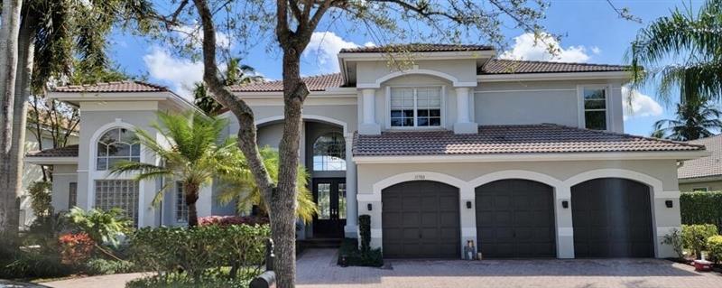 Three-car garage estate with a warm white stucco repaint